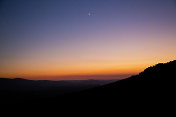 Atardecer / atardecer con degradación de colores desde anaranjados hasta azul oscuro y silueta de montaña en la parte inferior. 
