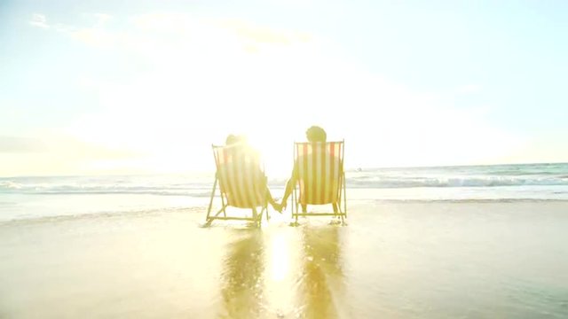 Relaxing Couple on Tropical Resort Luxury Vacation. Beach Chairs in the Sunset. 