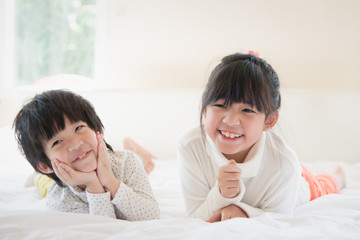 asian children lying on white bed