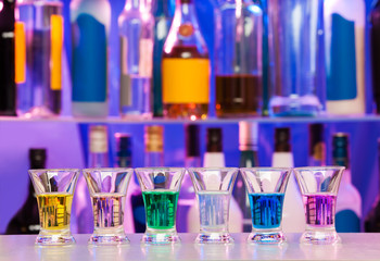 Big row of shots glasses with color drinks