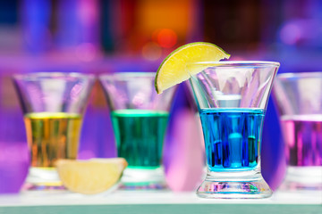 Several glasses with color drinks and lime in bar
