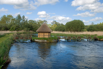 Obraz premium Traditional fishing Hut with eel traps on the River Test, in the Test Valley Hampshire, England on a summer afternoon.