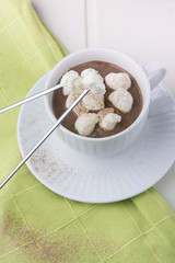 Cup of hot cacao with marshmallow on cotton serviette, close up