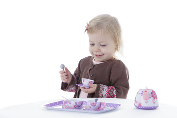 toddler girl playing with tea set, sipping tea, isolated on white background