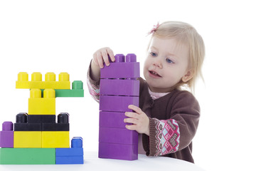 toddler girl playing with colored building blocks, holding in hands, isolated on white background