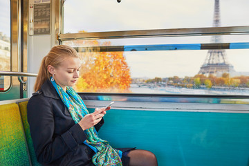 Beautiful young woman travelling in a train of Parisian underground and using her mobile phone