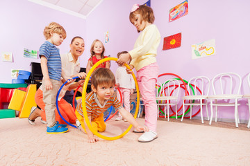 Active kindergarten class kids crawl though hoops