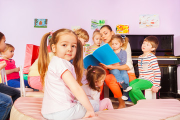 Group of kids listen to teacher reading book