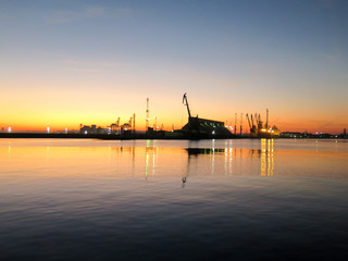 Fototapeta premium The shape of the crane and docks in the port at sunset