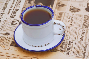 Vintage still life with coffee cup on the old newspaper