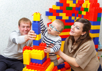 Father, mother and son build tower from bricks together
