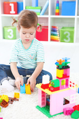 Fototapeta premium child girl playing with toys and builds constructor