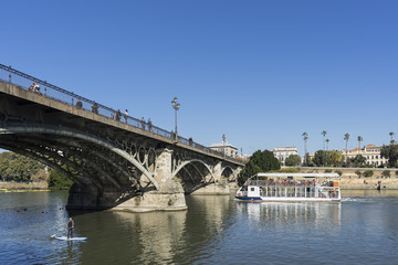 Fototapeta na wymiar El río Guadalquivir pasando por el puente de Triana en la ciudad de Sevilla