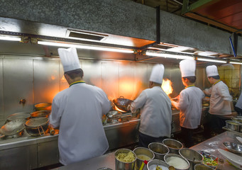 Crowded kitchen, a narrow aisle, working chef.