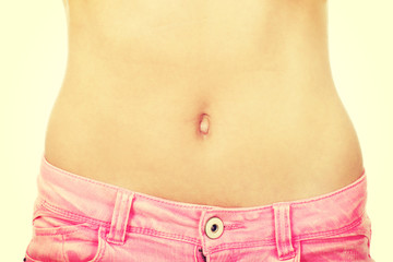Naklejka premium Slim woman wearing jeans showing belly.