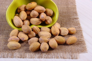 Pistachio nuts in bowl on white wooden table, healthy eating
