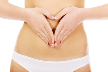 Young woman in white panties making heart shape on her belly