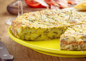 Spanish omelette and spinach with ham and cheese on old wooden t