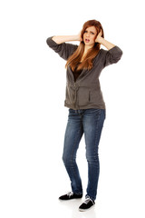 Fototapeta premium Angry teenage woman covering ears with hands
