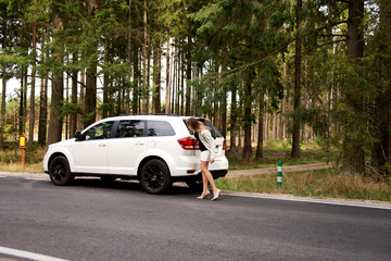 Young woman with broken car in the middle of forest