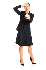 Shocked businesswoman holding alarm clock