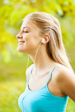 Young woman is listening music in park.