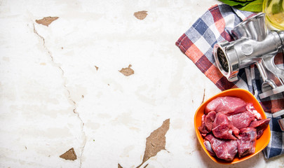 Raw meat with a hand grinder on the fabric.
