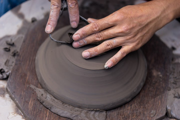 Hands working with clay on pottery wheel