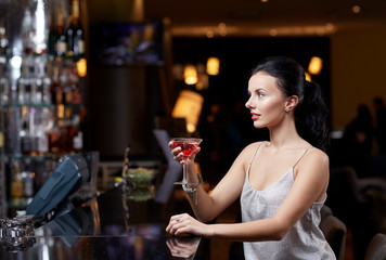 glamorous woman with cocktail at night club or bar