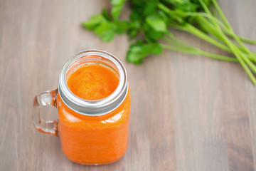 Healthy carrot smoothie in a jar on wooden background