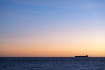 Fototapeta premium Silhouette of cargo ship on the horizon