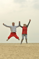 Mature couple jumping on beach