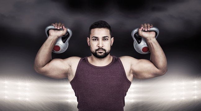 Composite image of muscular serious man lifting kettlebells