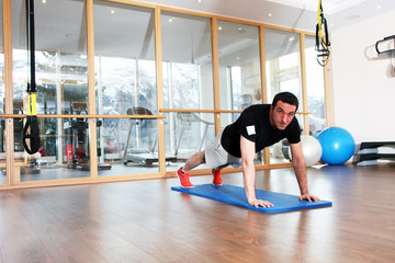 Fitnesstrainer macht Übungen auf Gymnastikmatte