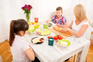 Obraz na płótnie Canvas Mother and children having breakfast at home