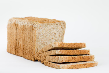 Angeschnittenes Vollkorntoastbrot vor weißem Hintergrund. Vier Scheiben liegen übereinander in Front.