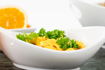 Eine Portion Rührei mit Petersilie in einer weissen Schale auf dunklem Holz