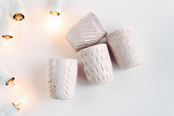 Obraz na płótnie Canvas stylish creative ceramics cups and christmas garland lights, hol