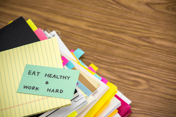 Eat Healthy Work Hard; The Pile of Business Documents on the Des