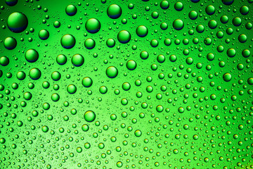 Fototapeta na wymiar Green water drops on glass surface texture.