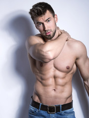 handsome young bodybuilder with toned body posing shirtless