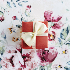 Obraz na płótnie Canvas simple surprise little box with bow on stylish flower paper, ho