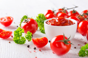 Bowl of tomato sauce and cherry tomatoes on wooden table.