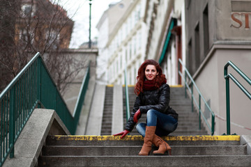 Beautiful woman with red hair sitting on stairs