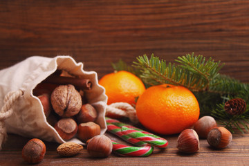 Christmas spirit: nuts, tangerines, Christmas tree, nuts, a flashlight on a dark wooden background