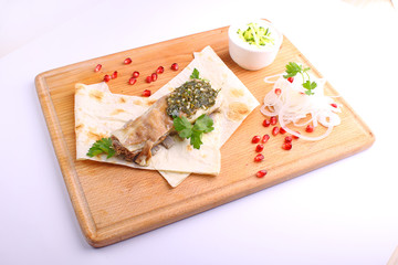 roasted meat with pita pomegranate and onion on a wooden cutting board