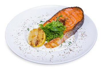 Grilled salmon steak with spinach in white plate, top view