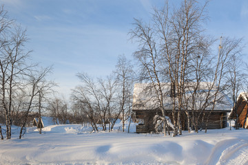 Snow Covered Houses and bare trees on field