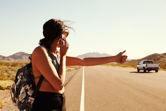 Woman On Vacation Hitchhiking Along Road Using Mobile Phone