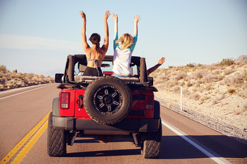 Rear View Of Friends On Road Trip Driving In Convertible Car